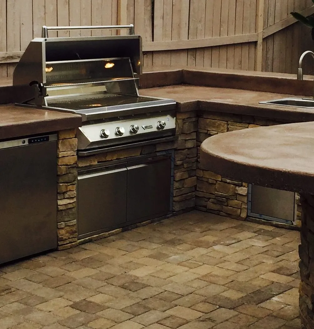 Stainless built-in grill and storage doors set into a stacked-stone outdoor kitchen